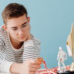 Young man with eyeglasses examines his medals and trophies, reflecting success.